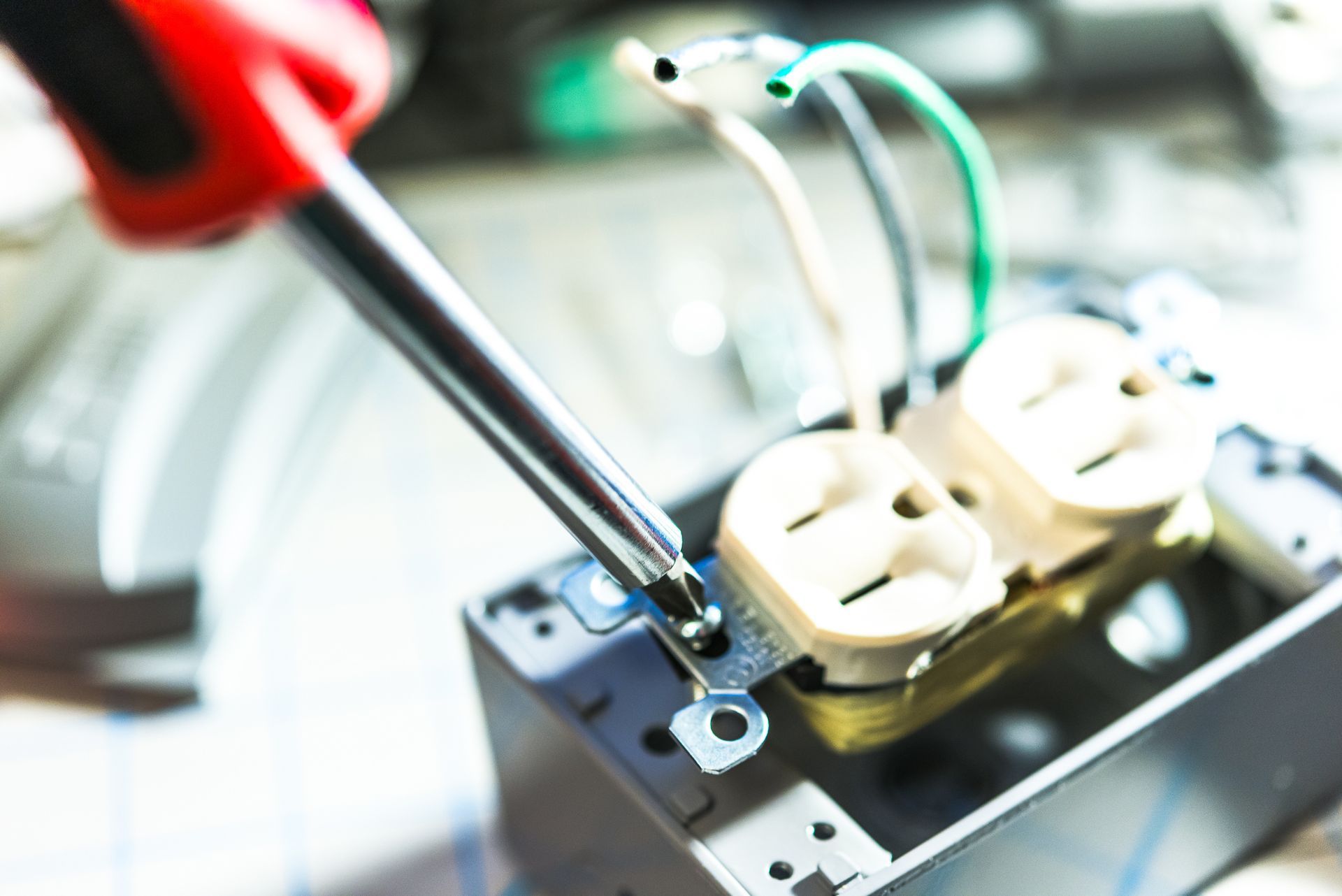Electrician using a screwdriver to install an electrical outlet, close-up.