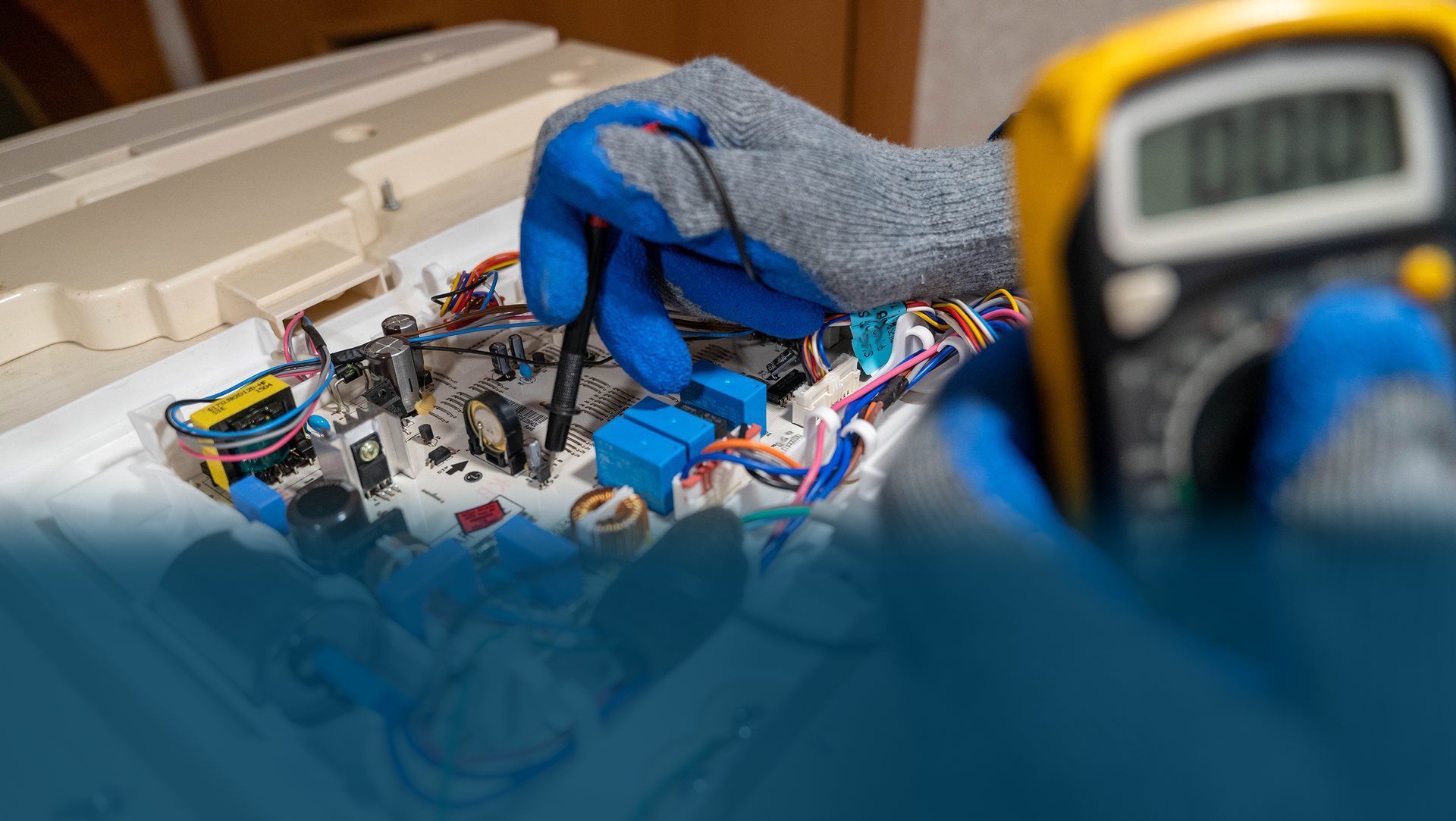 Person wearing blue gloves tests a circuit board with a multimeter.