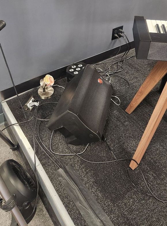 A speaker is sitting on a carpet next to a wooden table.