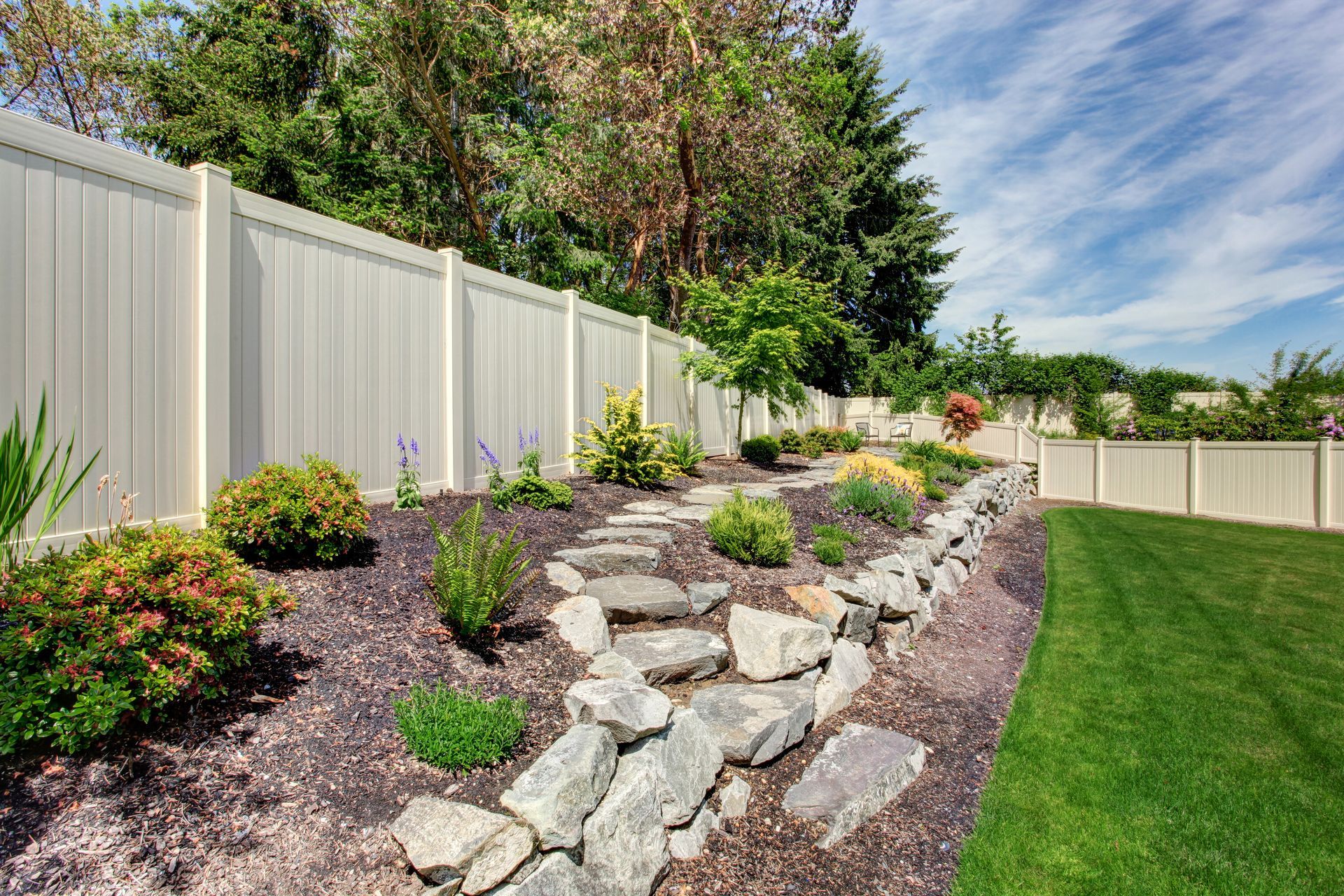 A large wooden painted white fence surrounding lush landscaping