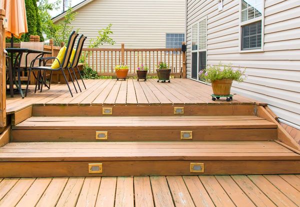 Stained wooden deck with stairs leading up to a fully furnished outdoor living space