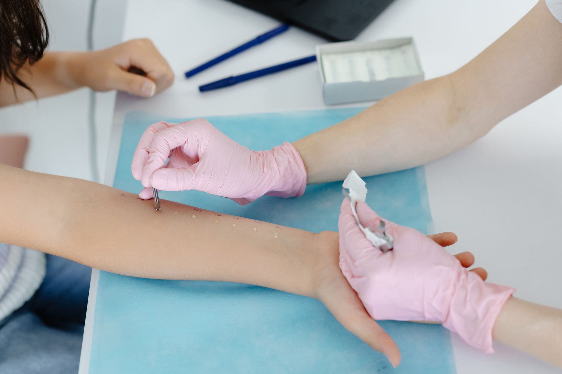 A doctor with pink gloves does an allergy test on the arm of a child. A doctor with pink gloves does an allergy test on the arm of a child.