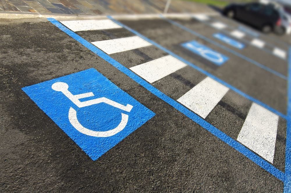 A person is painting a handicap sign on the ground
