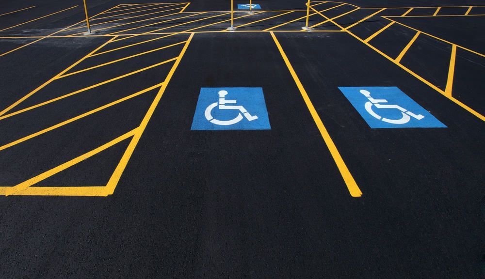 A person is painting a handicap sign on the ground