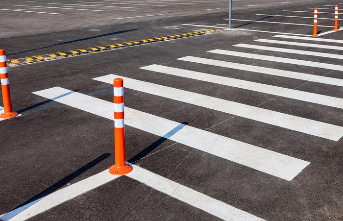 A close up of a crosswalk with orange and white poles.