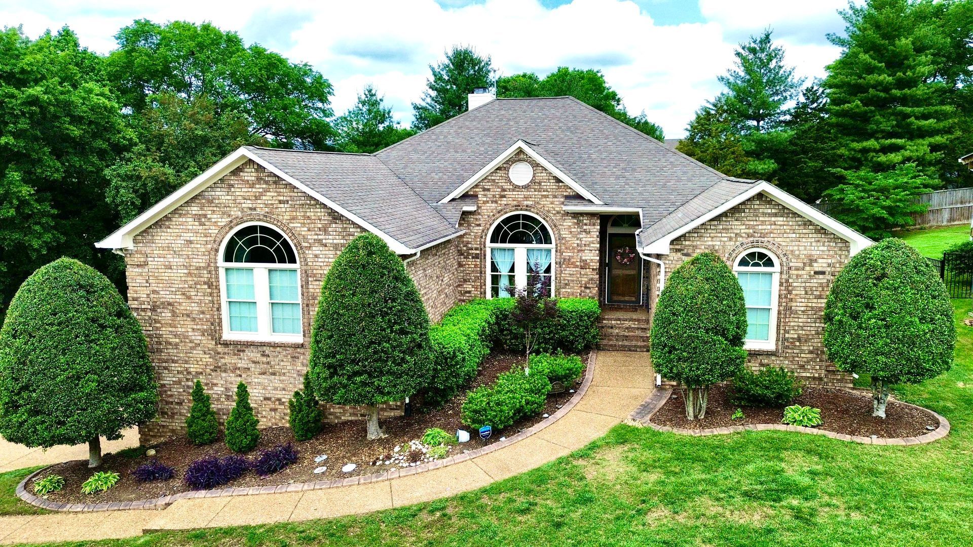 A large brick house with a lot of trees in front of it.