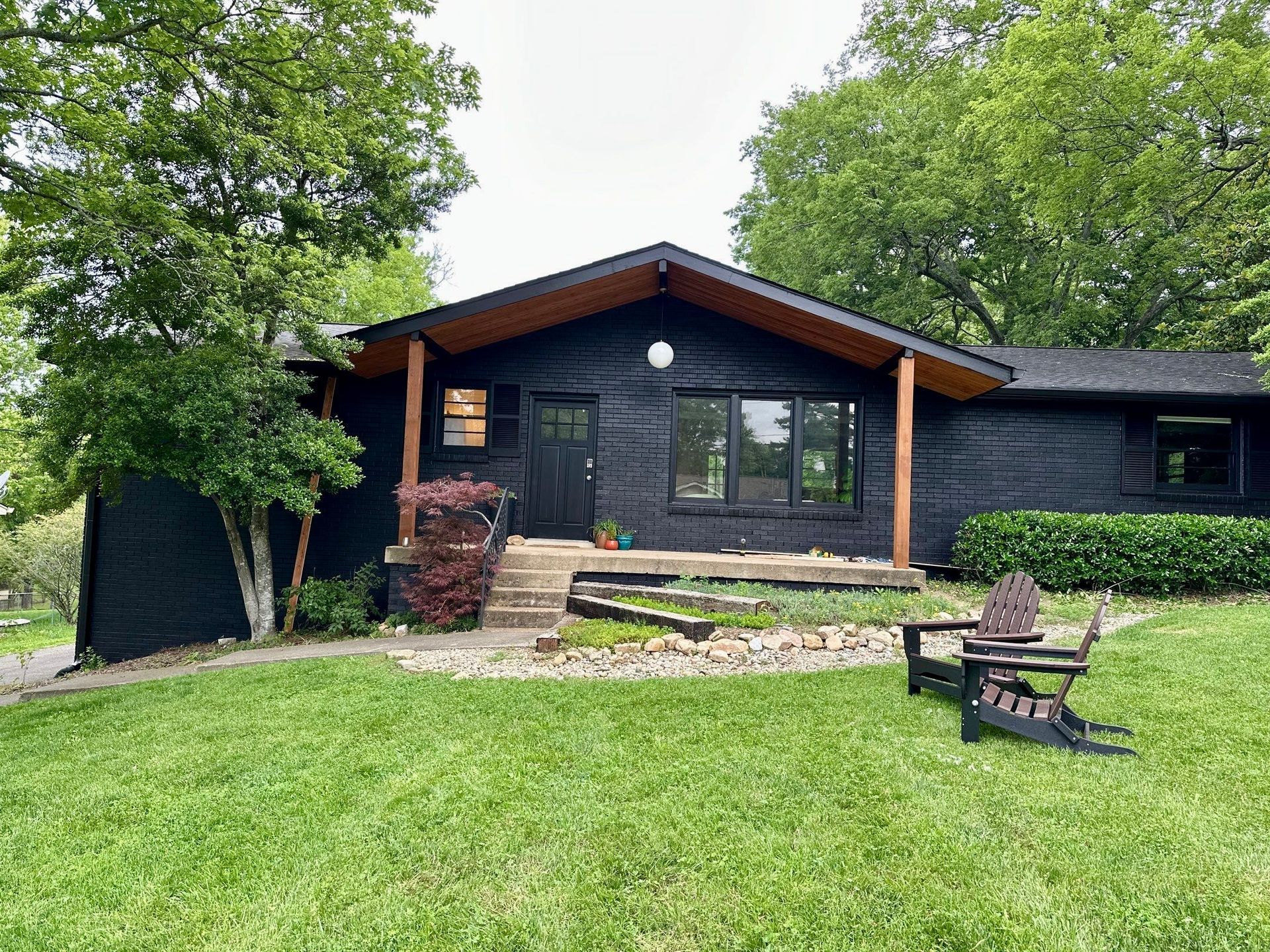 A black house with a porch and chairs in front of it.