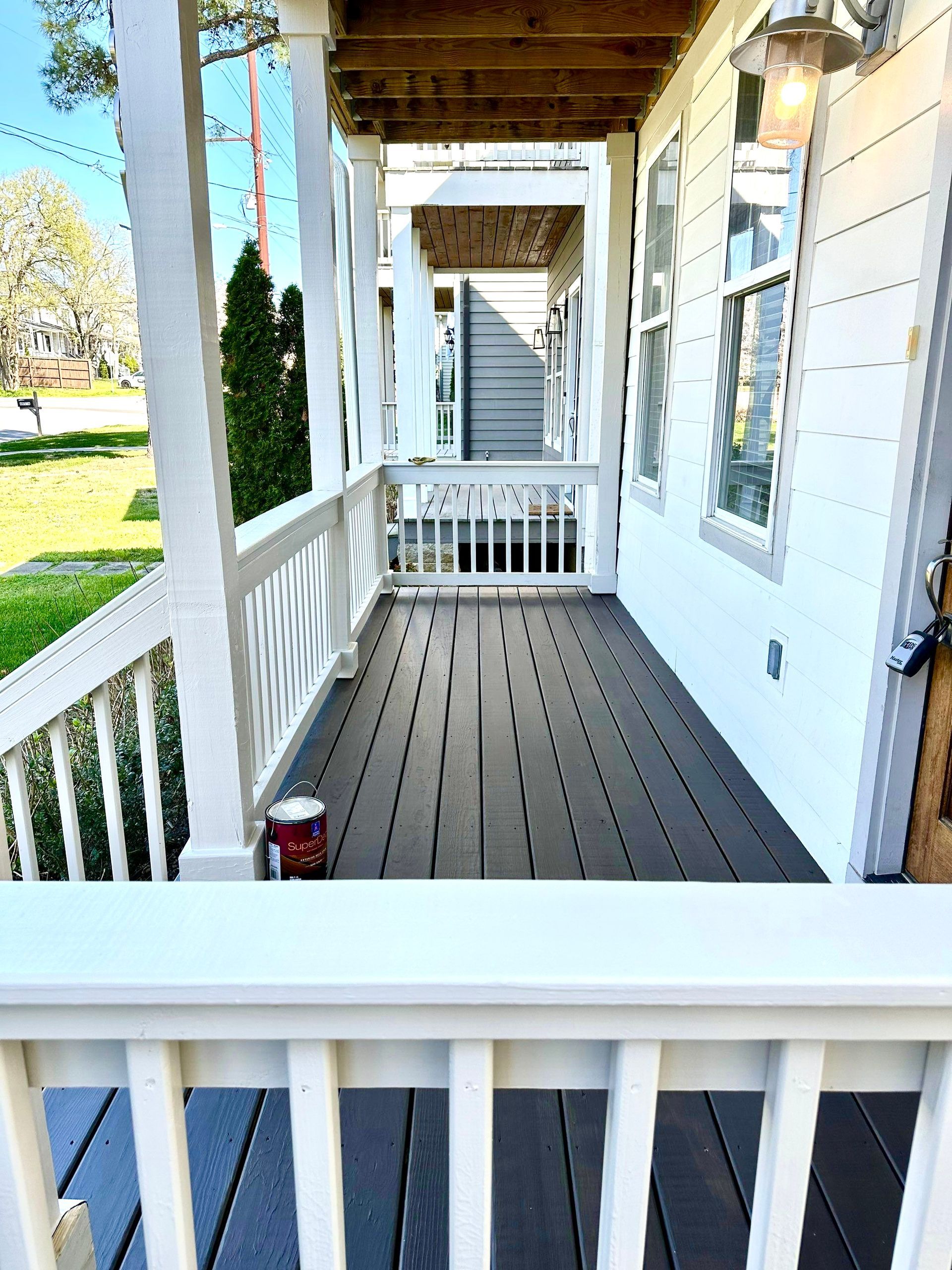 A porch with a white railing and a bucket of paint on it