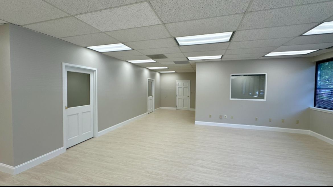 A large empty room with white walls and hardwood floors