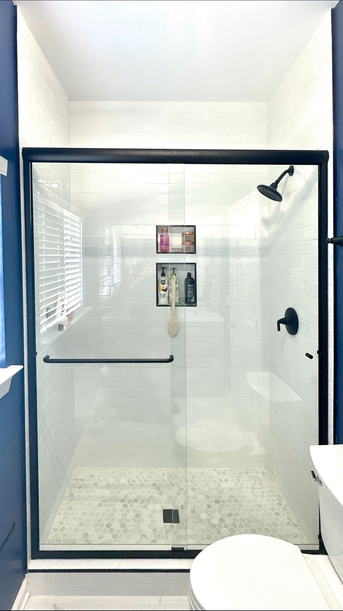 A bathroom with a sliding glass shower door and a toilet.