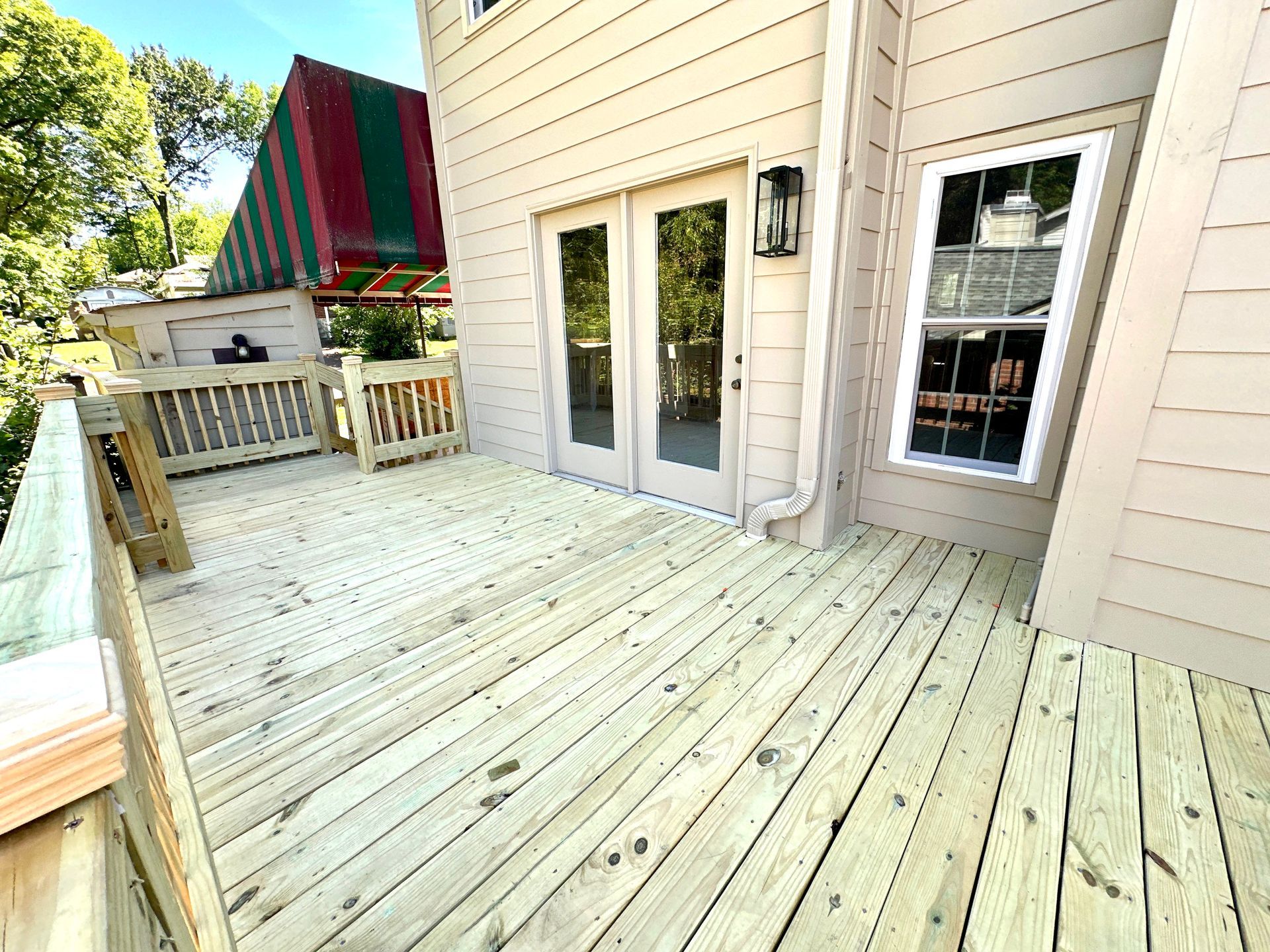 A large wooden deck with sliding glass doors and a striped awning.