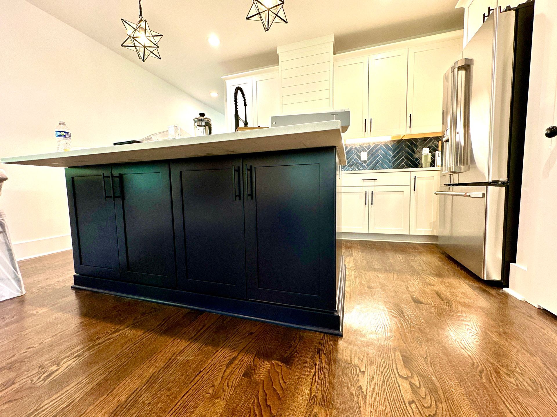 A kitchen with blue cabinets , white cabinets , stainless steel appliances and hardwood floors.