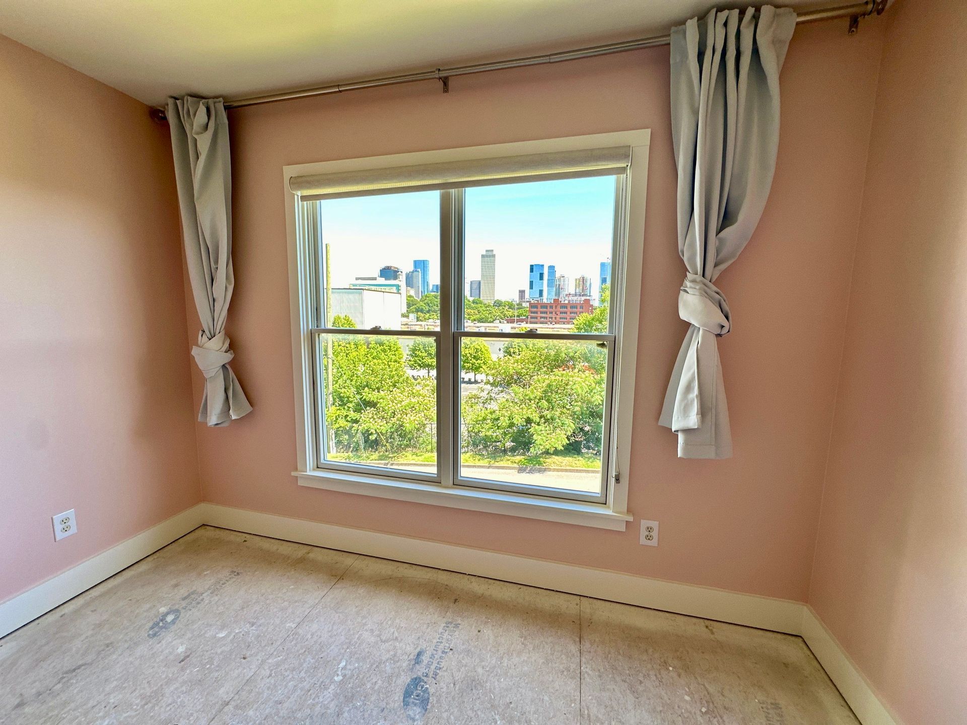 A bedroom with pink walls and a large window with a view of the city in Nashville, TN