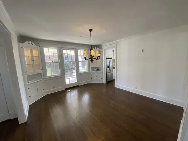 An empty living room with hardwood floors and a chandelier.
