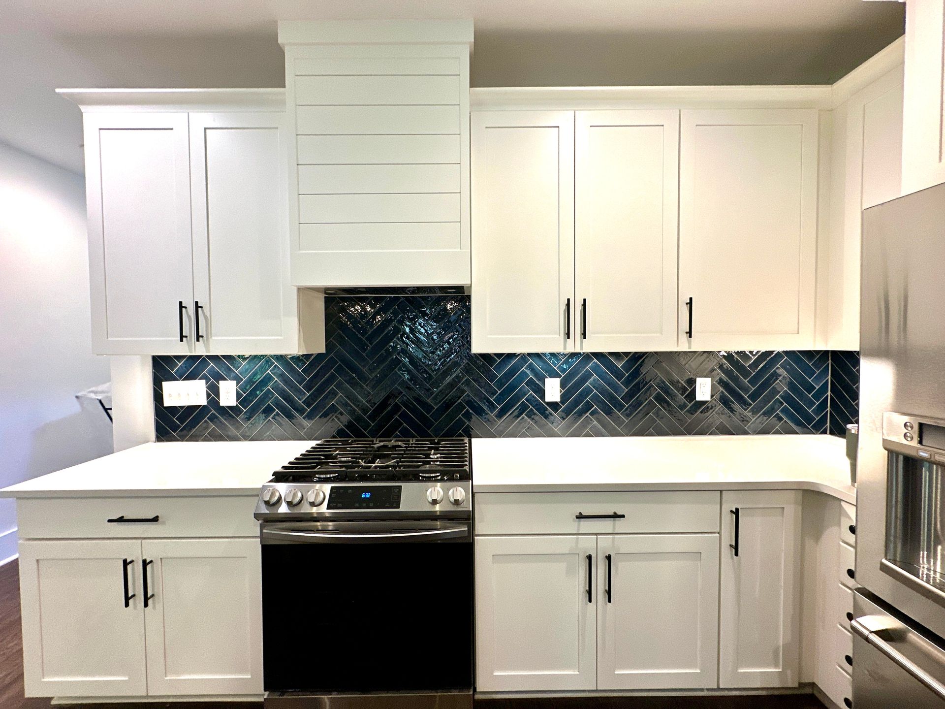 A kitchen with white cabinets , a stove , and a refrigerator.