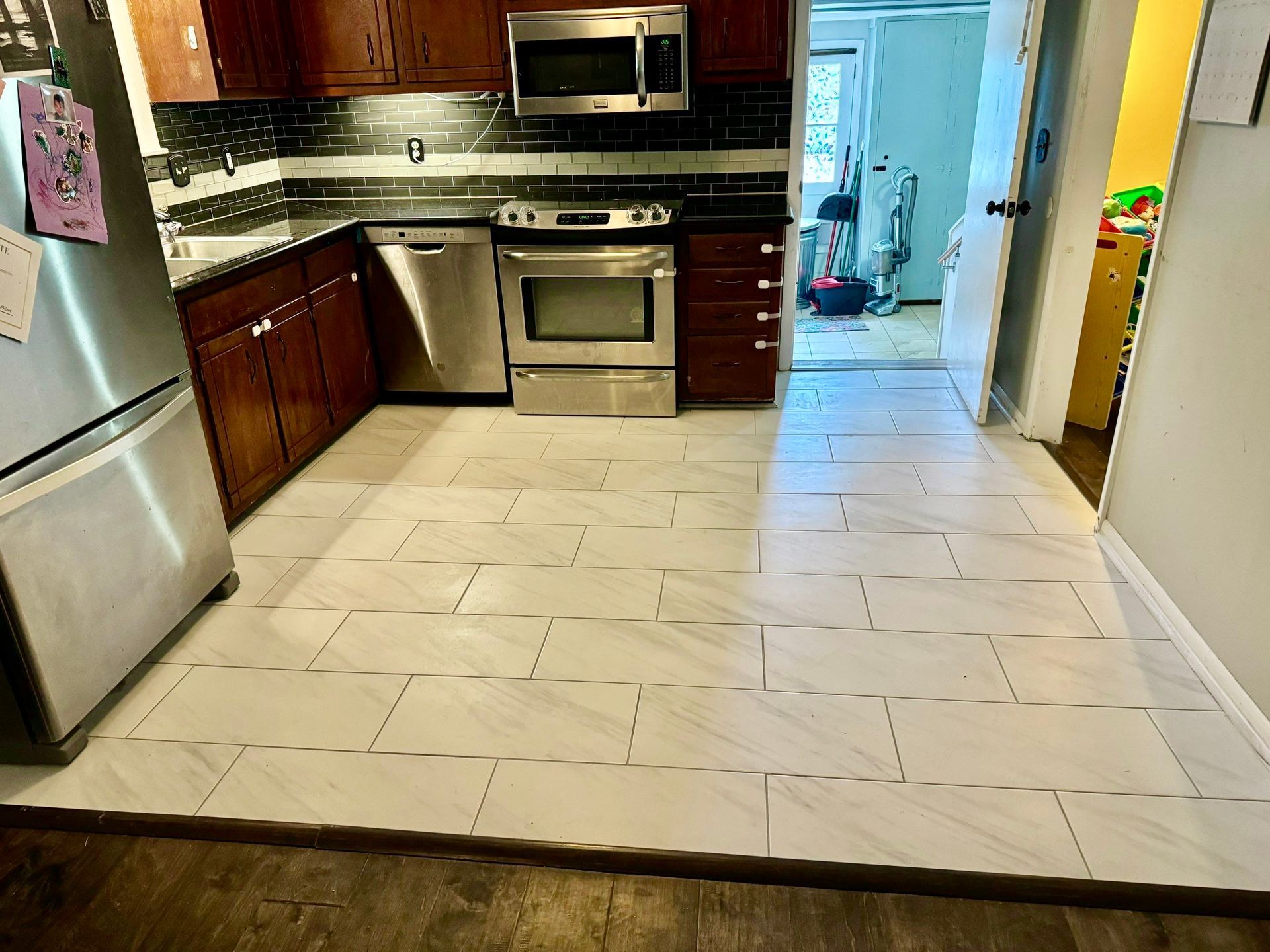 A kitchen with stainless steel appliances and a tiled floor.