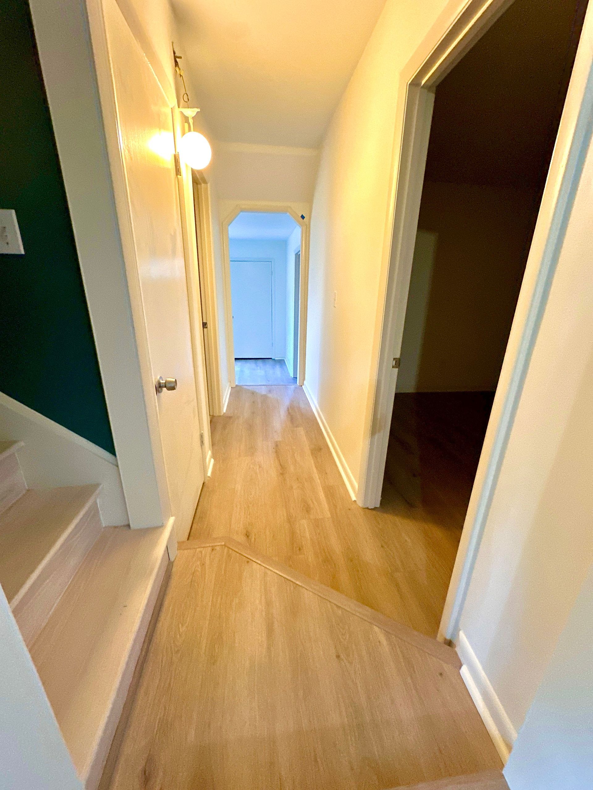 A hallway with hardwood floors and stairs in a house.
