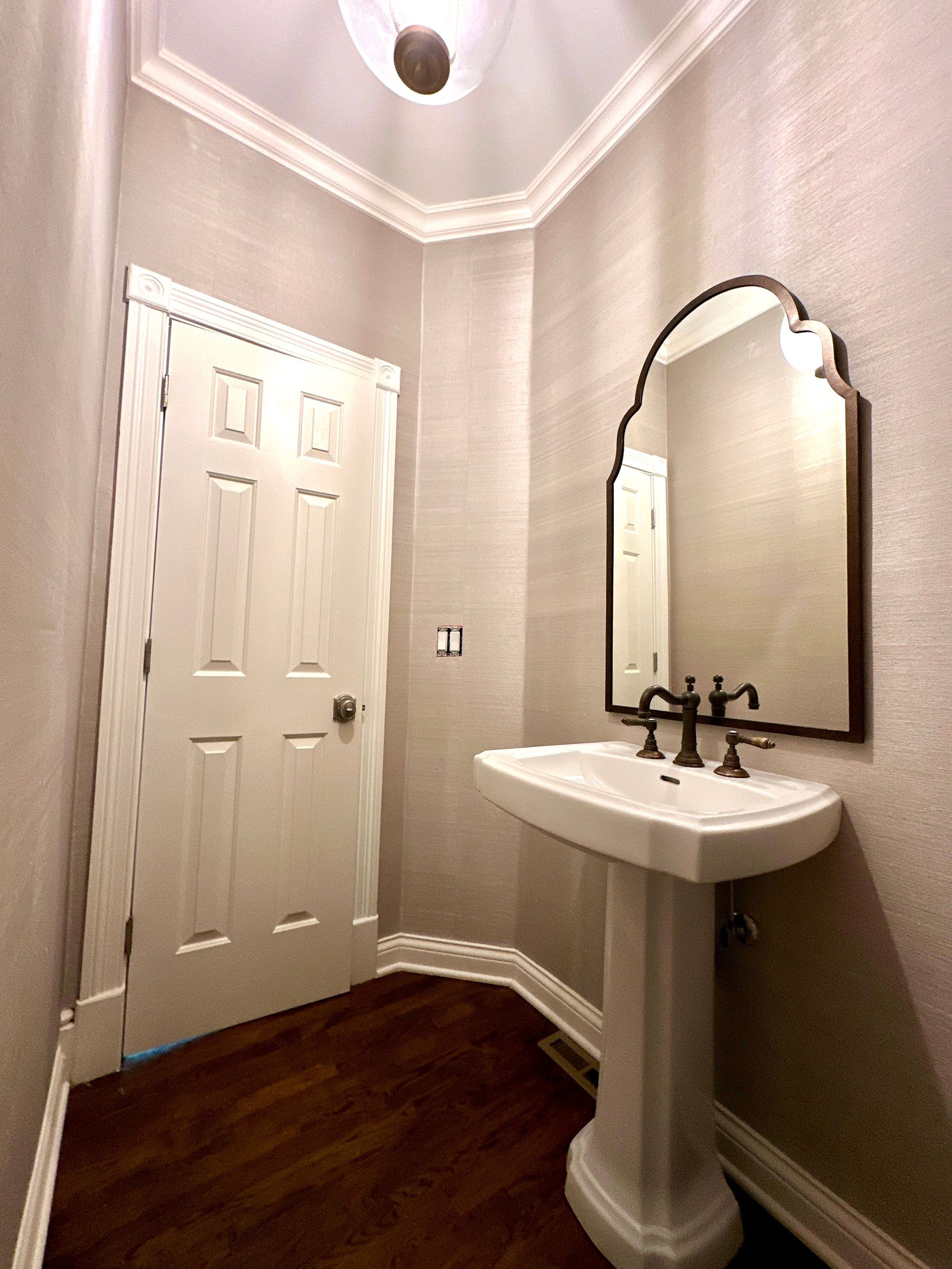 A bathroom with a pedestal sink and a mirror