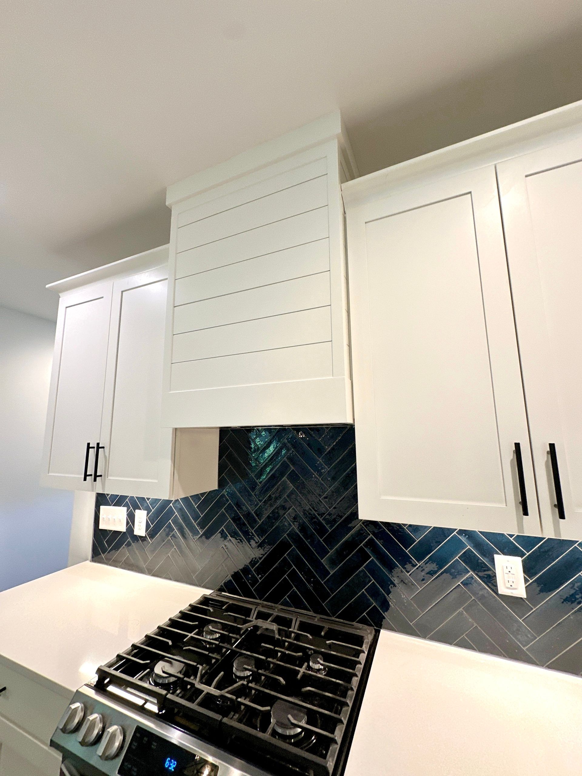 A kitchen with white cabinets and a stove top oven