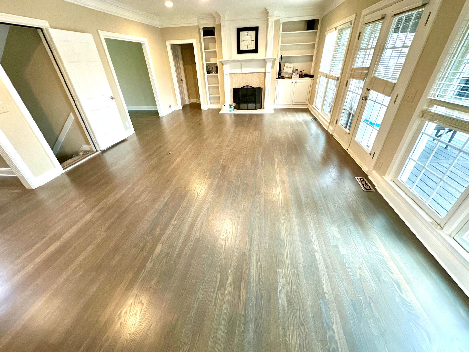 An empty living room with hardwood floors and a fireplace.