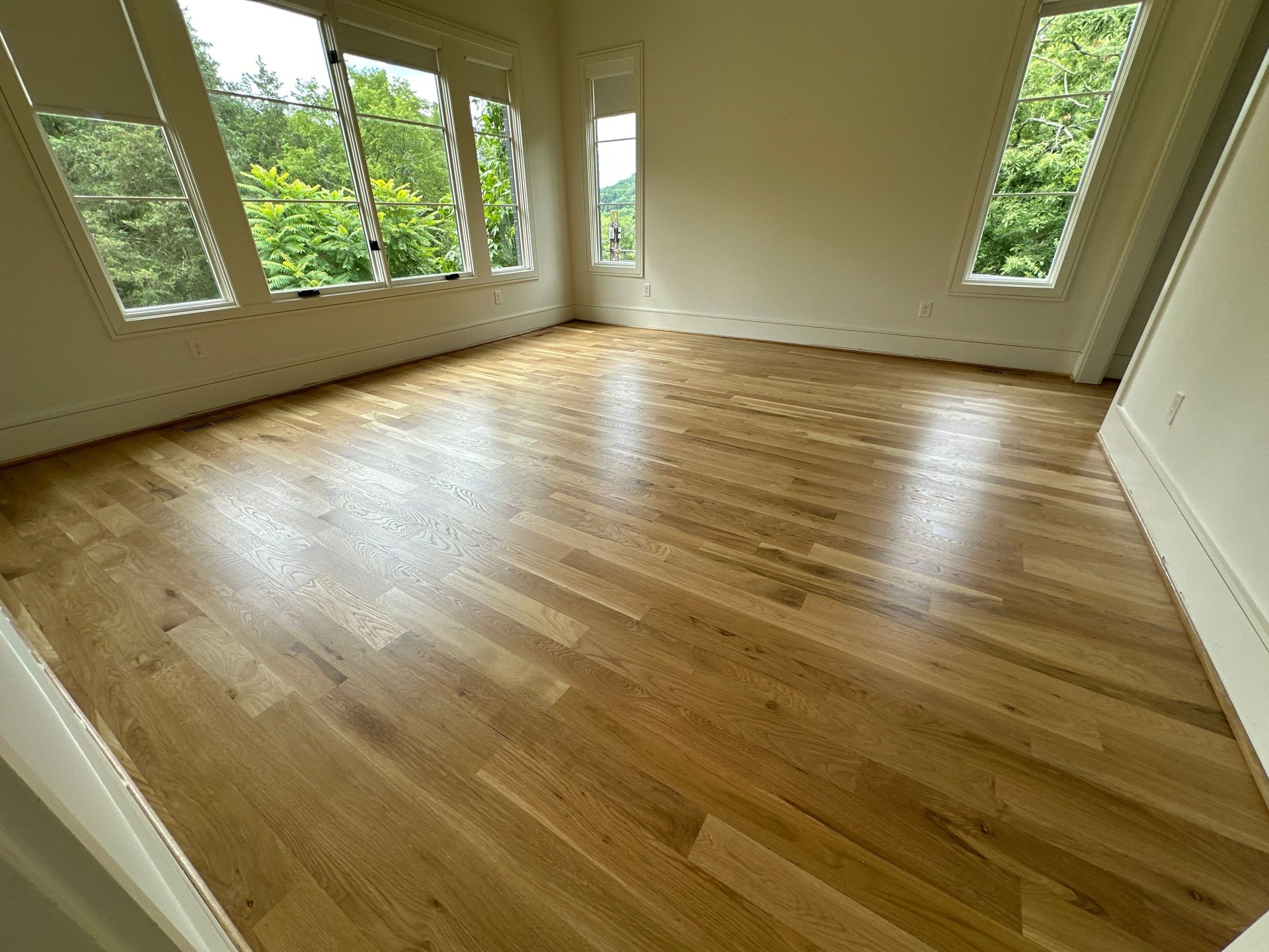 A large empty room with hardwood floors and lots of windows.