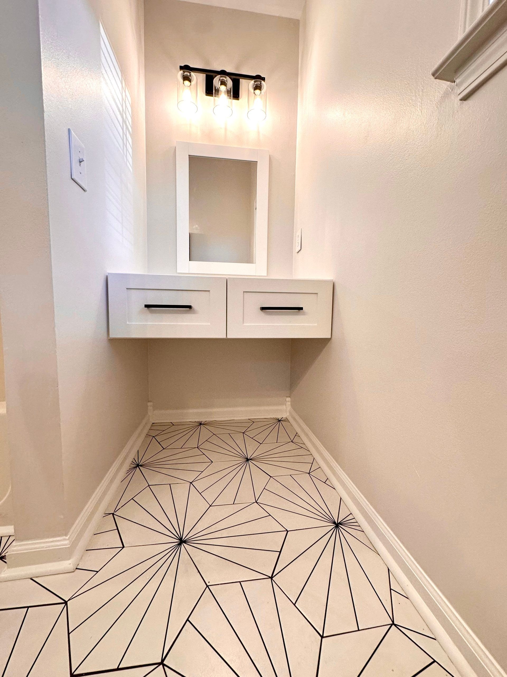 A bathroom with a vanity and a mirror on the wall.