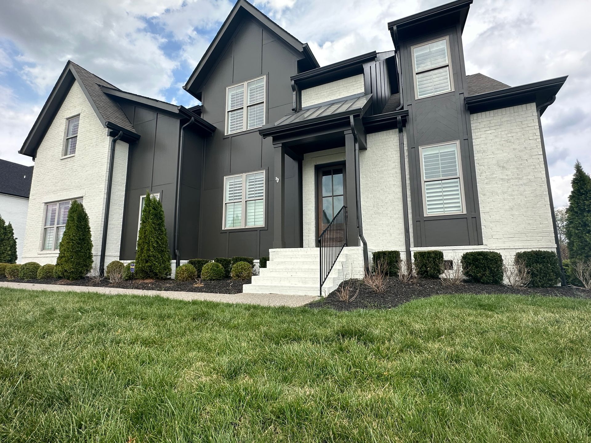 A large black and white house with a lush green lawn in front of it in Nashville, TN