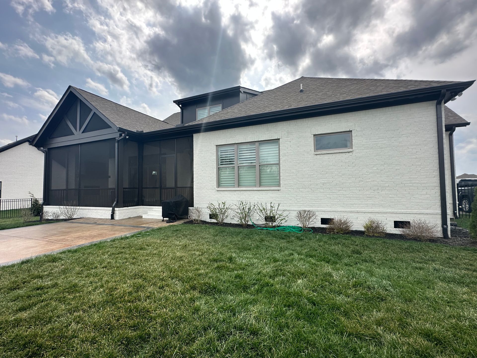 A white house with a screened in porch and a large lawn in front of it in Nashville, TN