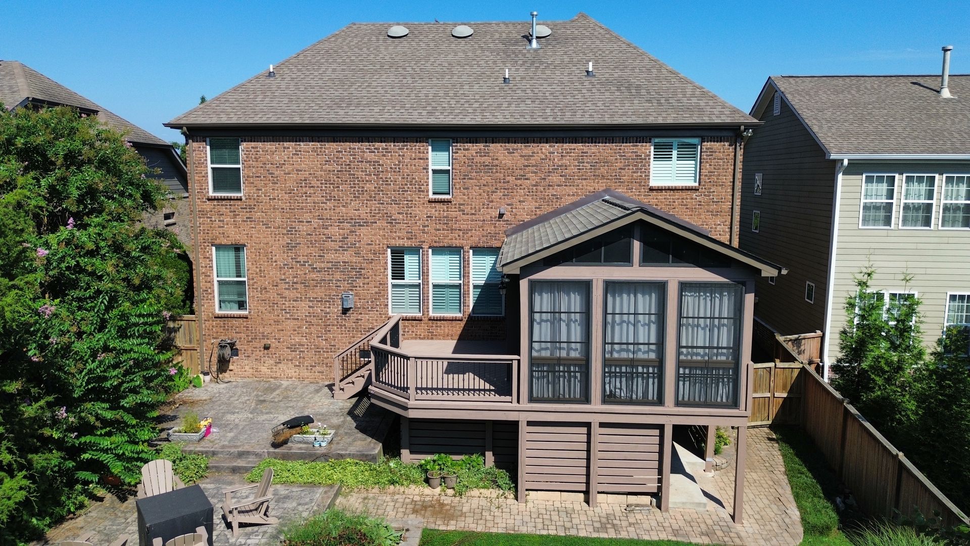 An aerial view of a brick house with a screened in porch.