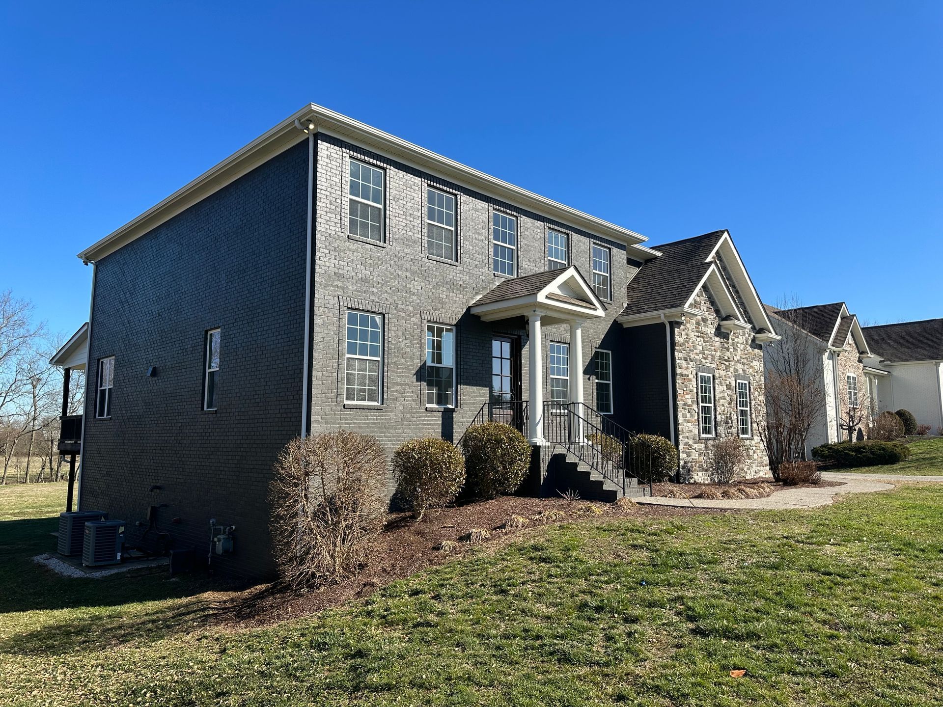 A large brick house with a lot of windows is sitting on top of a lush green field in Nashville, TN