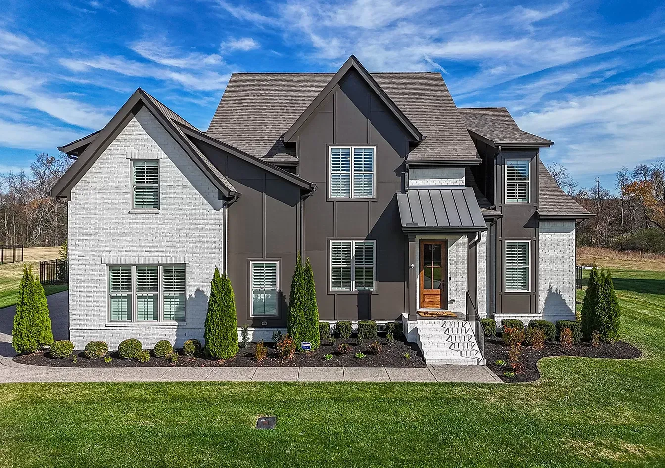A large house with a lot of windows is sitting on top of a lush green field.