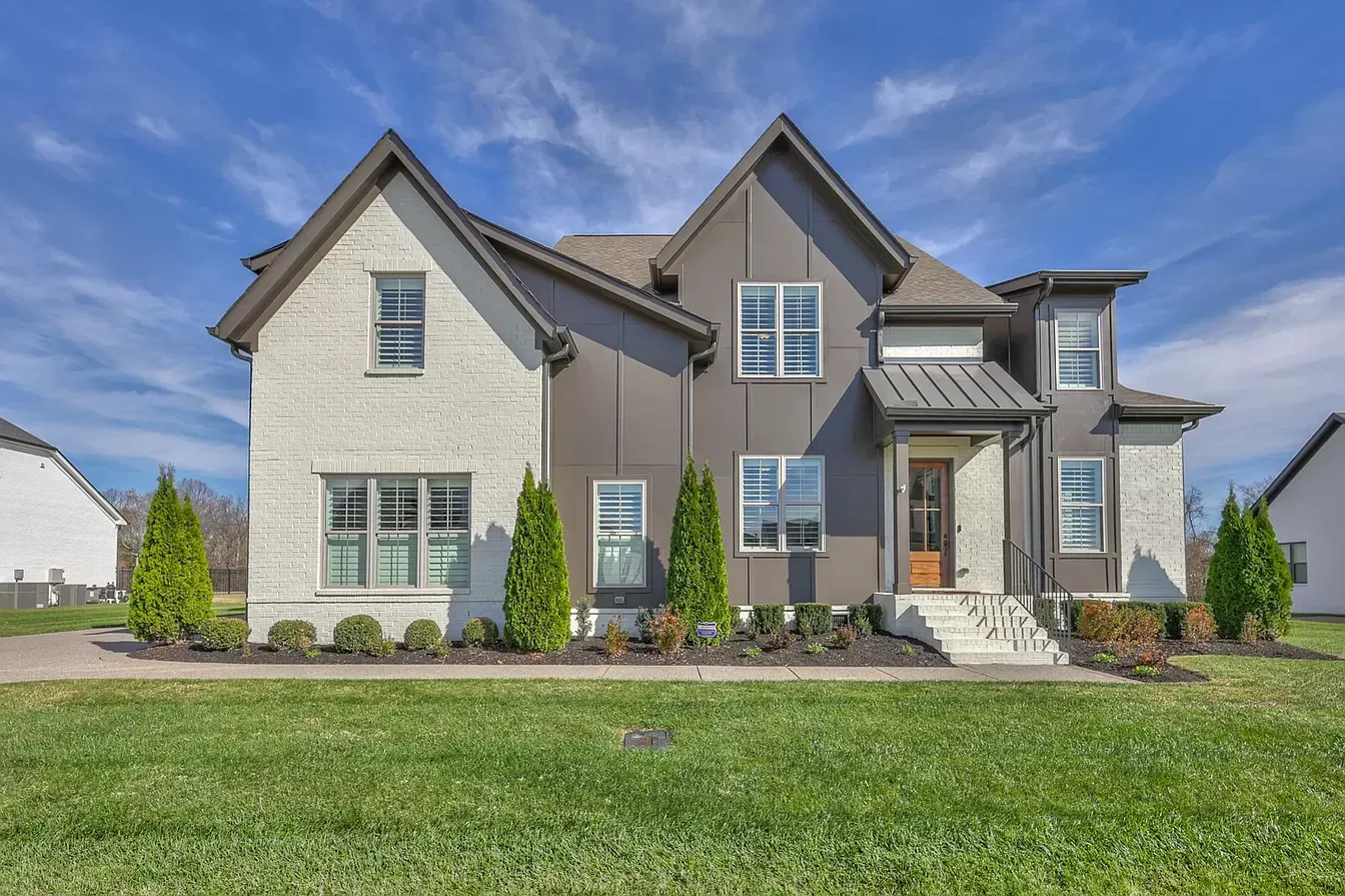 A large house with a lot of windows is sitting on top of a lush green field.