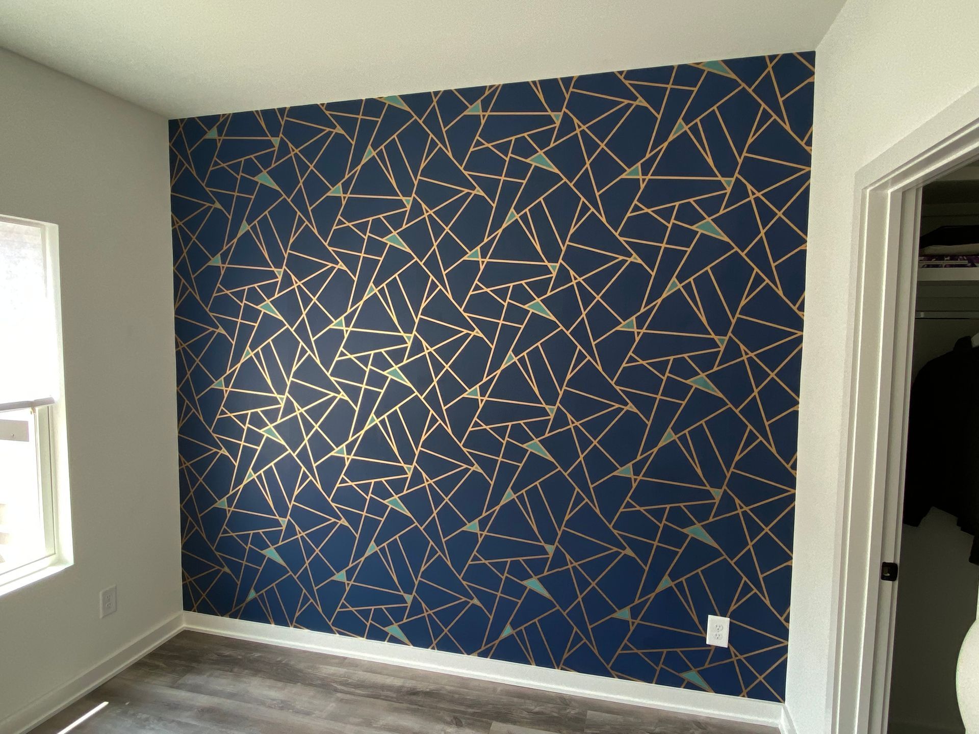 A bedroom with a blue and gold geometric wallpaper on the wall in Nashville, TN