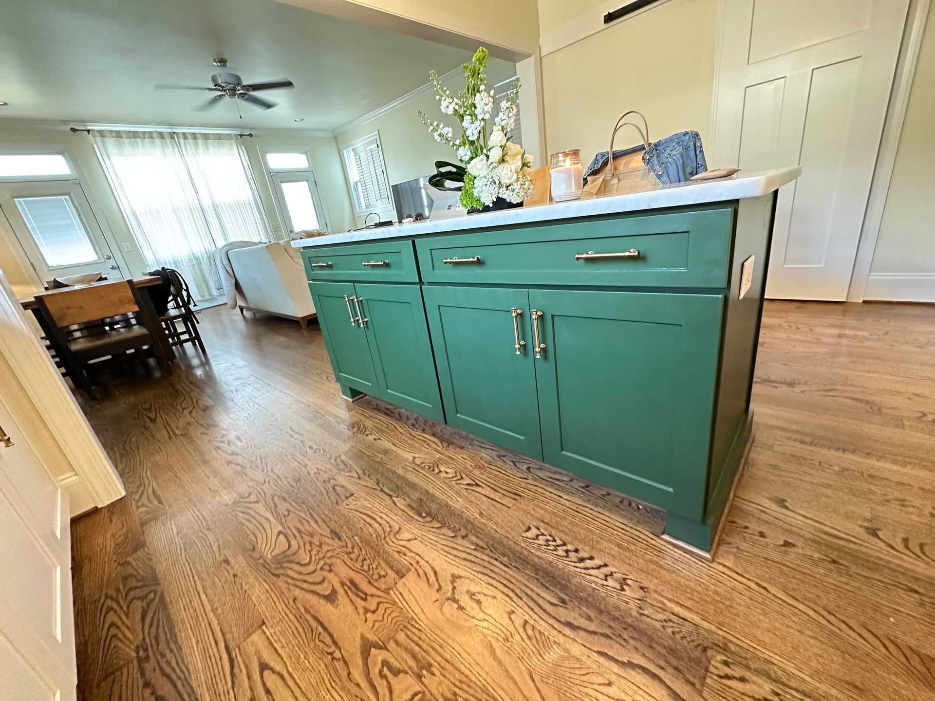 A kitchen with green cabinets and a wooden floor.