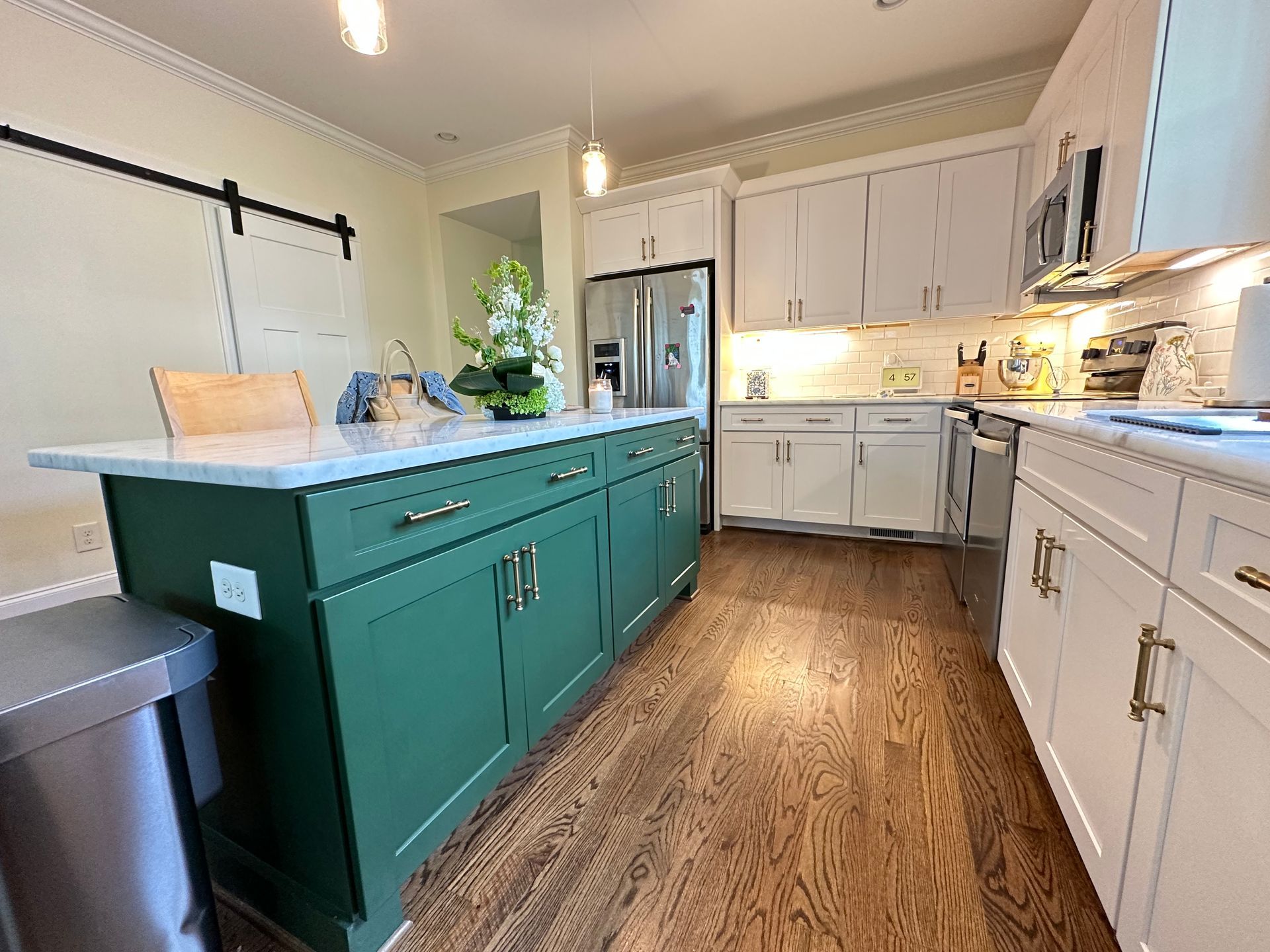 A kitchen with green cabinets , white cabinets , hardwood floors and stainless steel appliances in Nashville, TN