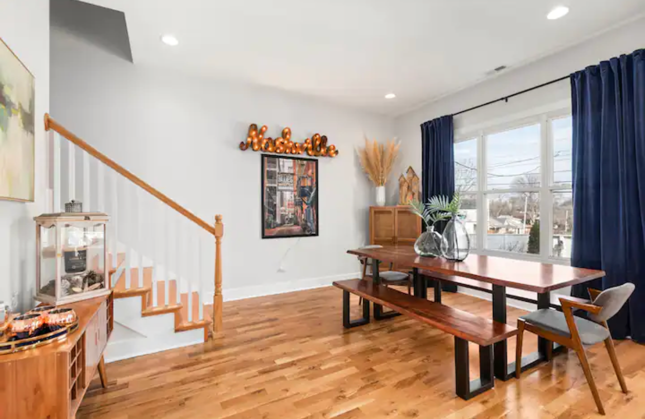 A dining room with a table , bench , chairs and stairs.