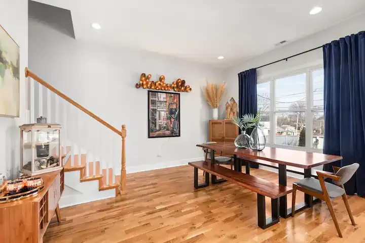 A dining room with a wooden table and benches and stairs.