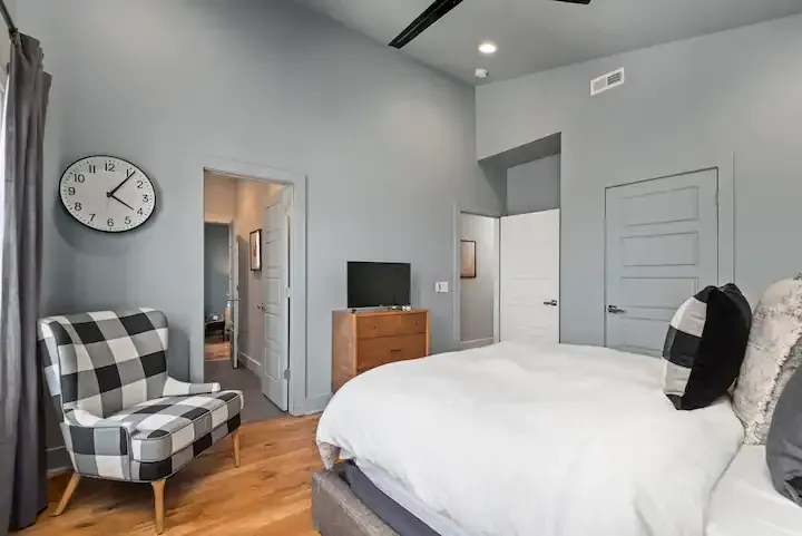 There is a clock on the wall above the bed in the bedroom.