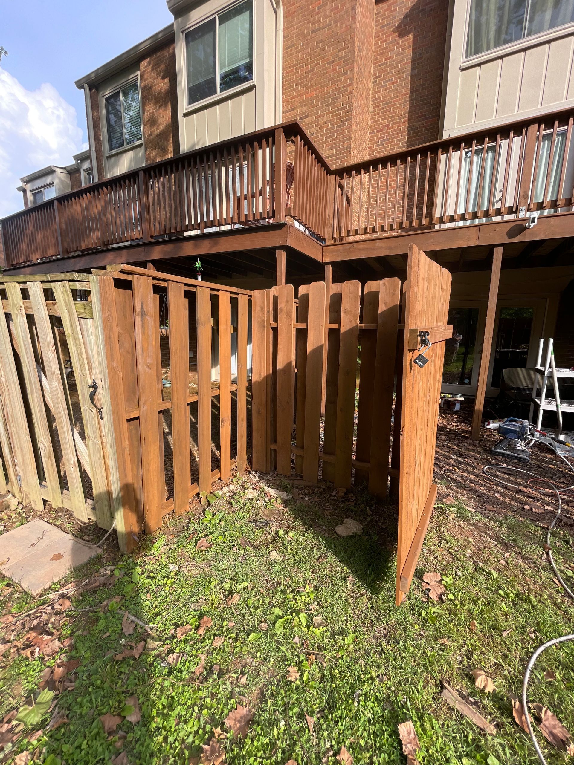 A wooden fence is sitting in front of a house with a deck.