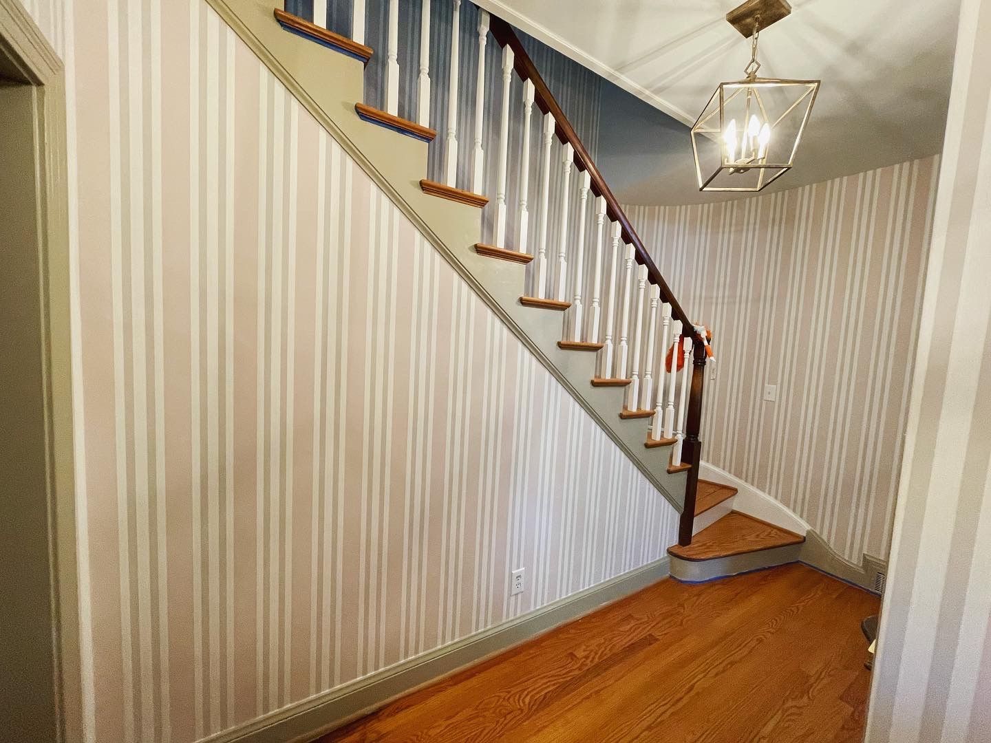 A staircase in a hallway with striped wallpaper and hardwood floors in Nashville, TN