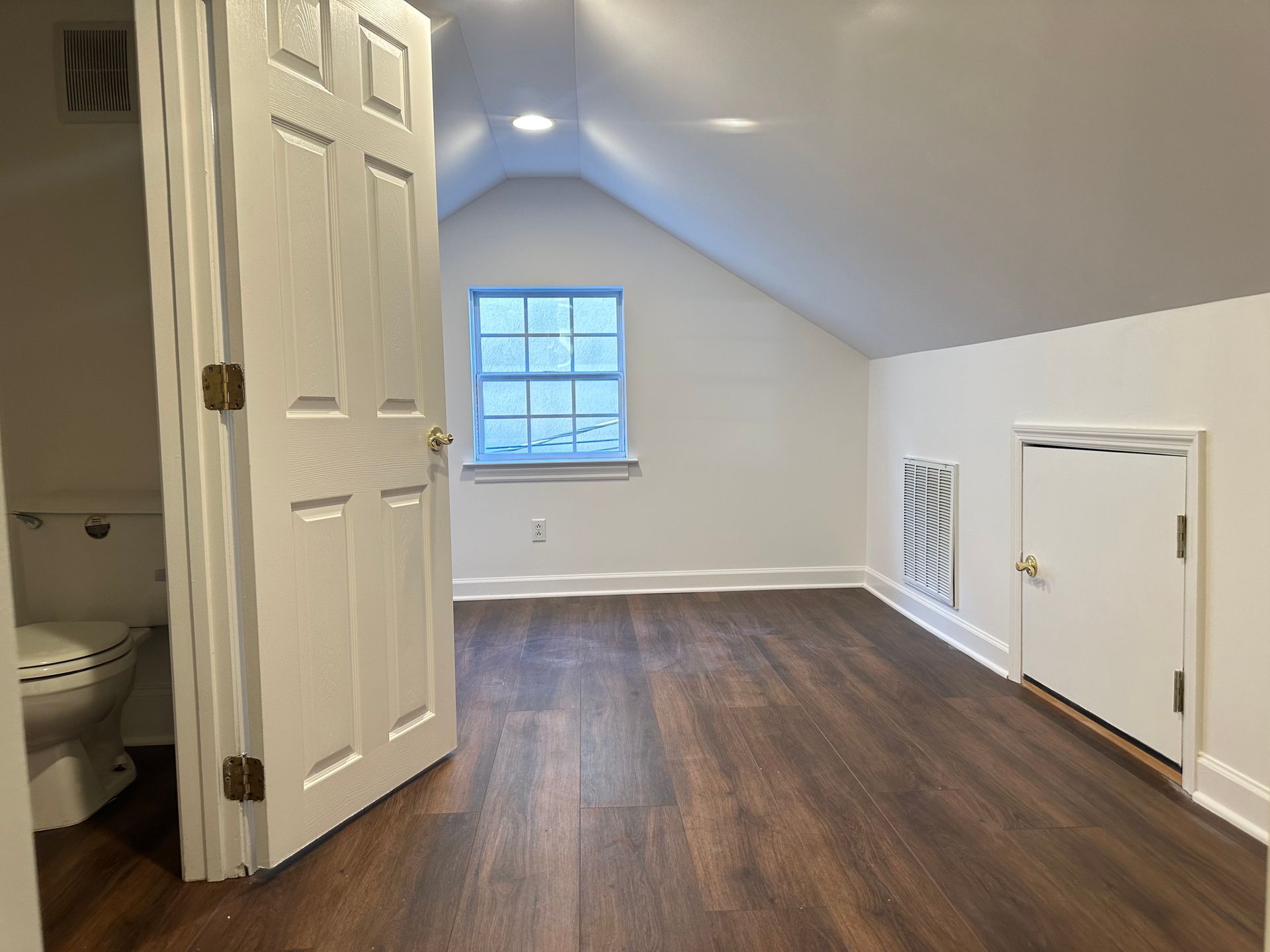 An empty room with a toilet and a window