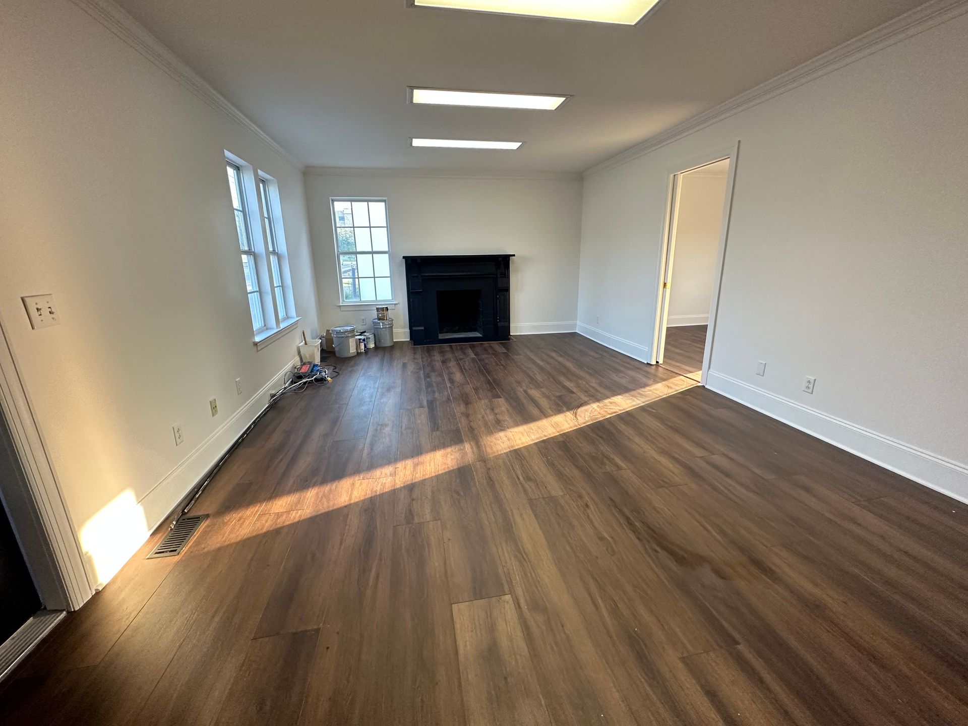 An empty living room with hardwood floors and a fireplace.