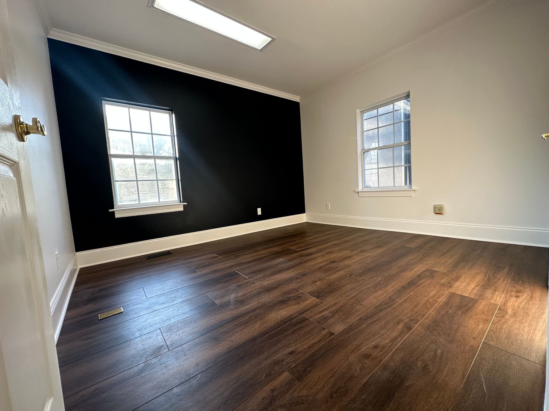 An empty room with hardwood floors and two windows in Nashville, TN