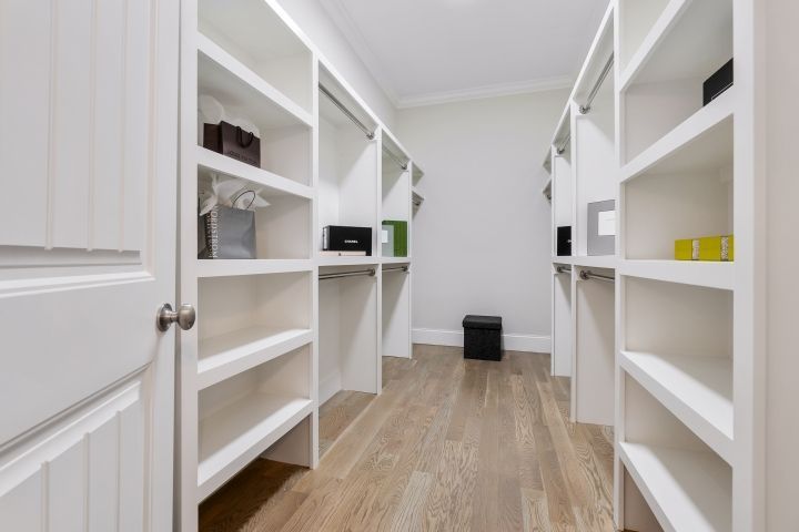 A walk in closet with lots of shelves and a wooden floor.