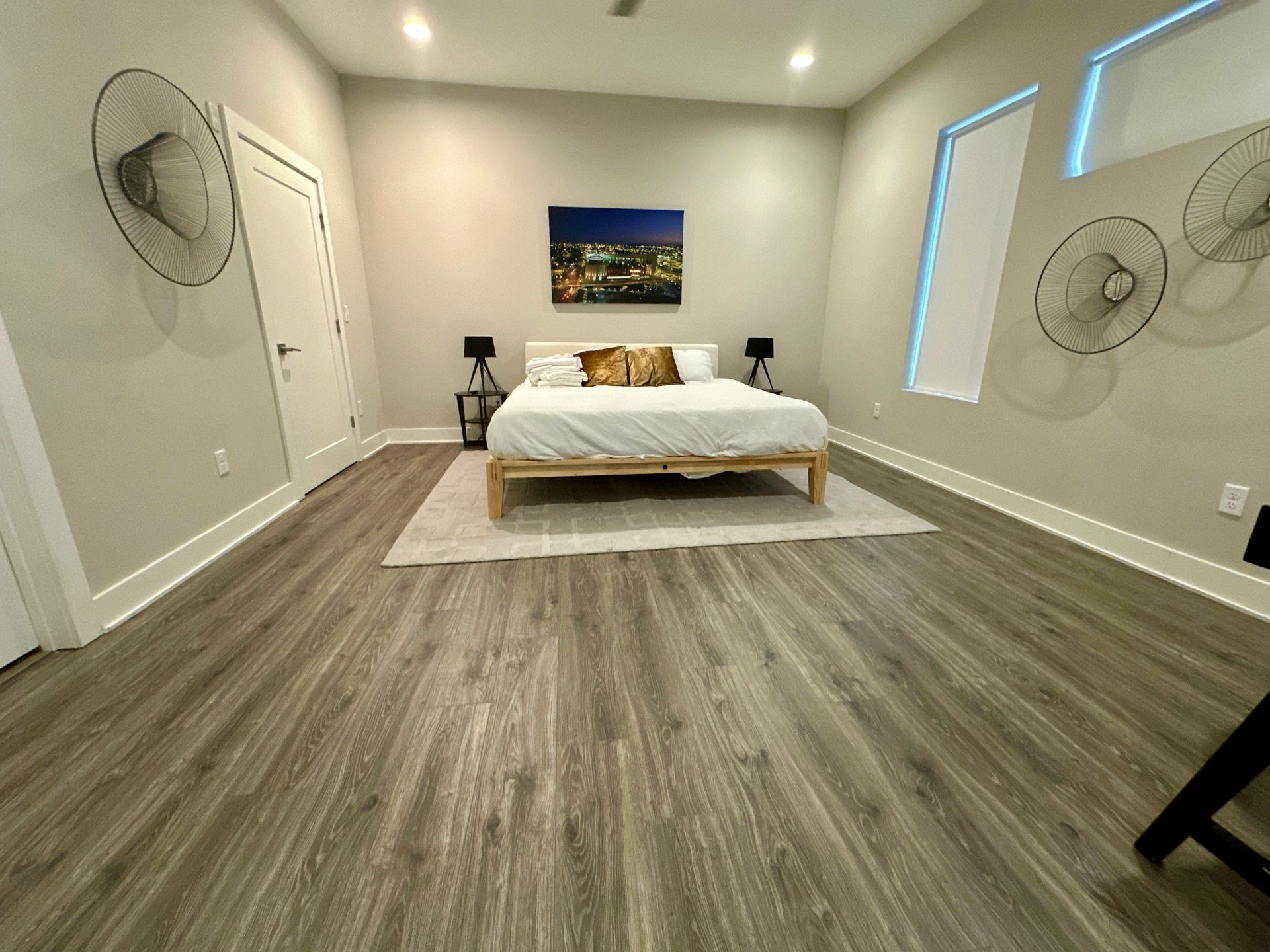 A bedroom with a bed , a rug , and a painting on the wall.