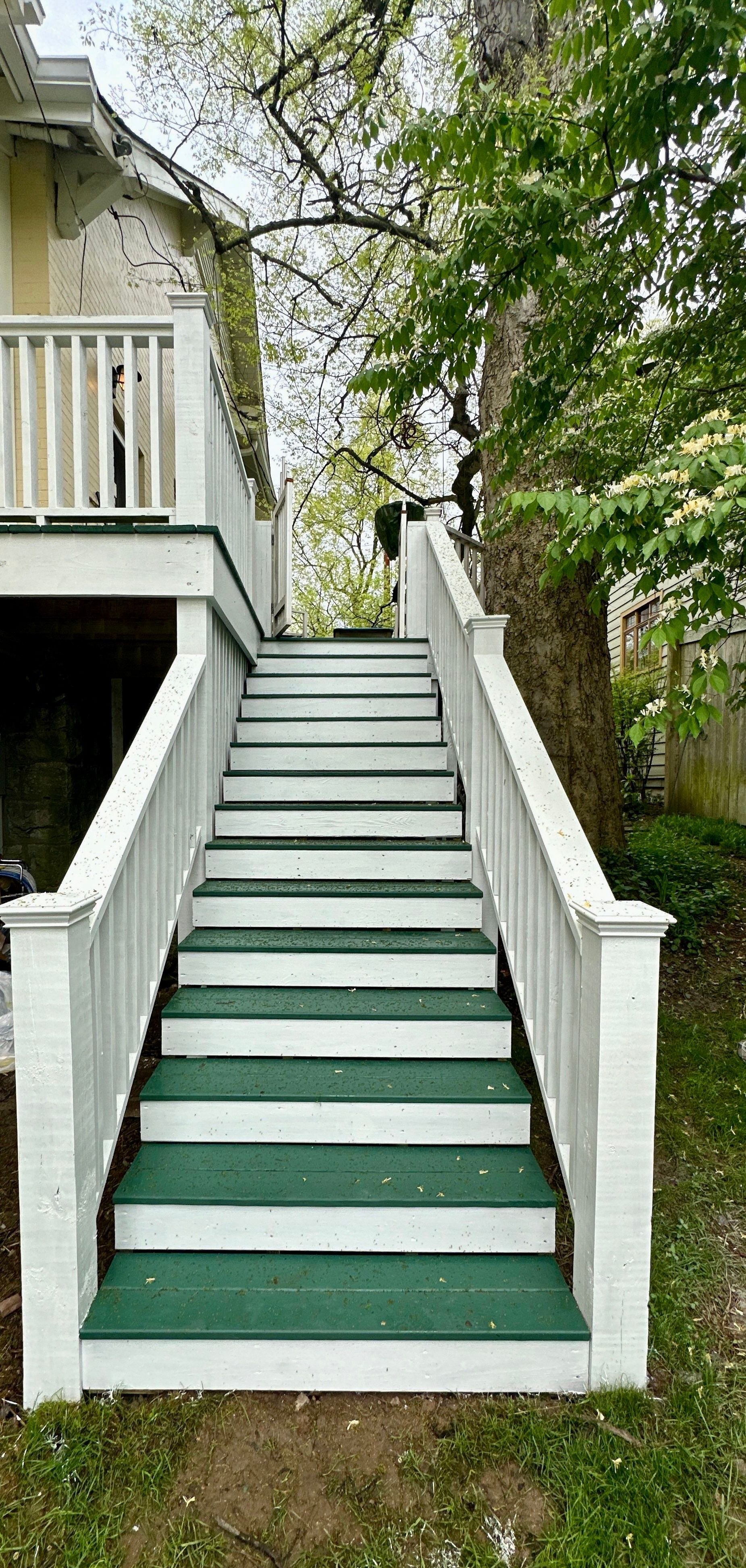 A white deck with green stairs leading up to it.