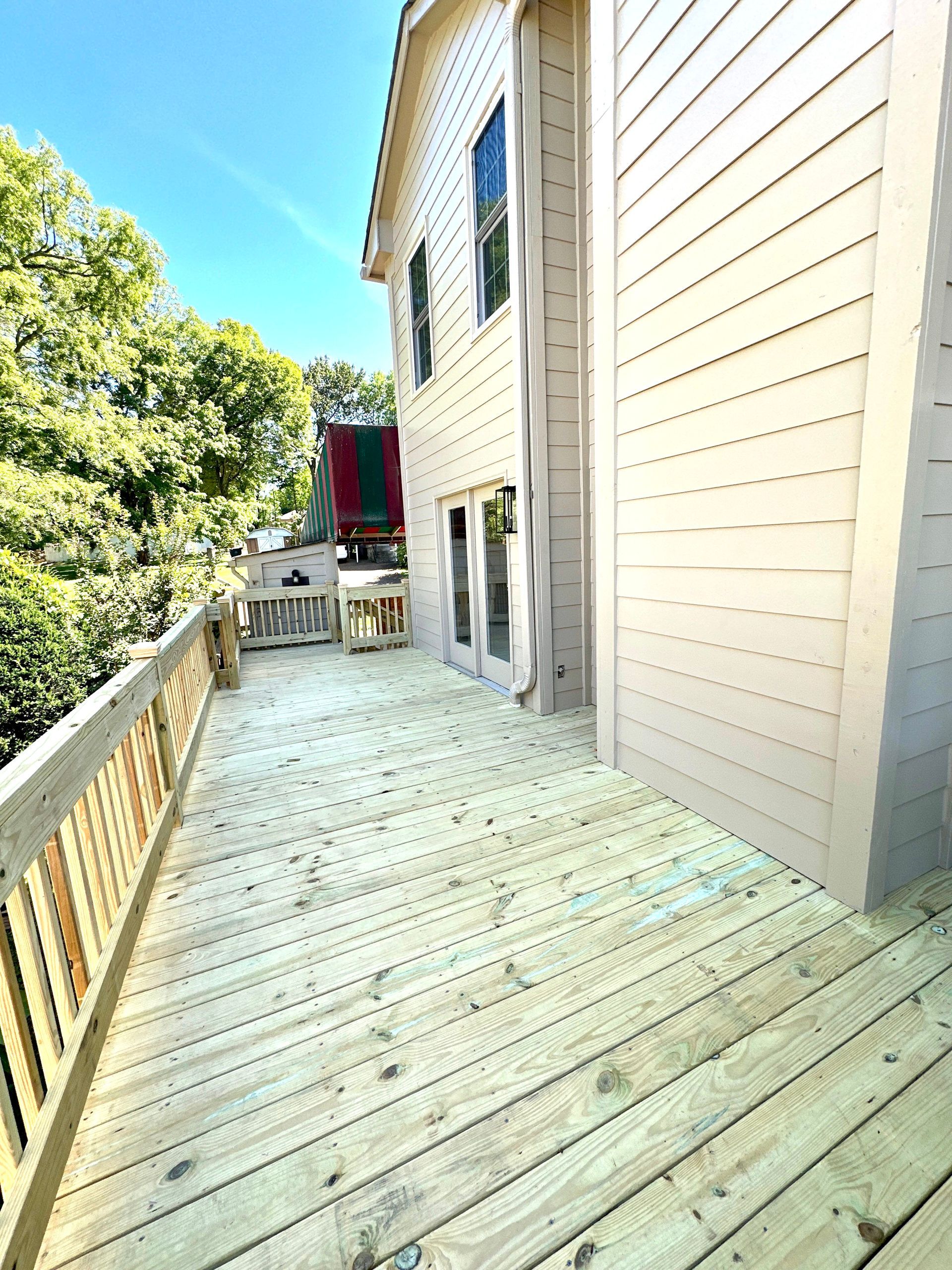 There is a large wooden deck in front of a house.