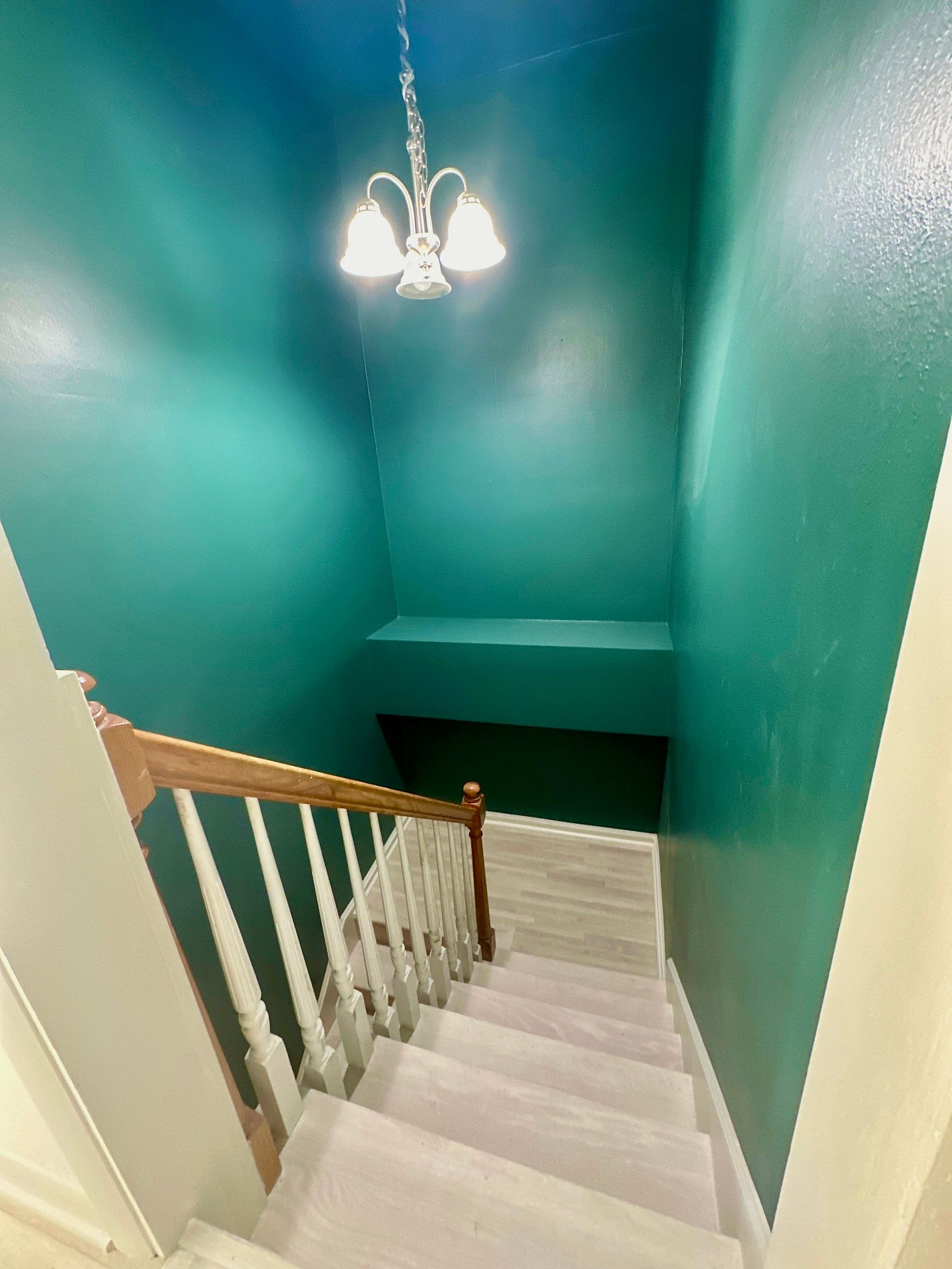 A staircase with green walls and a chandelier hanging from the ceiling in Nashville, TN