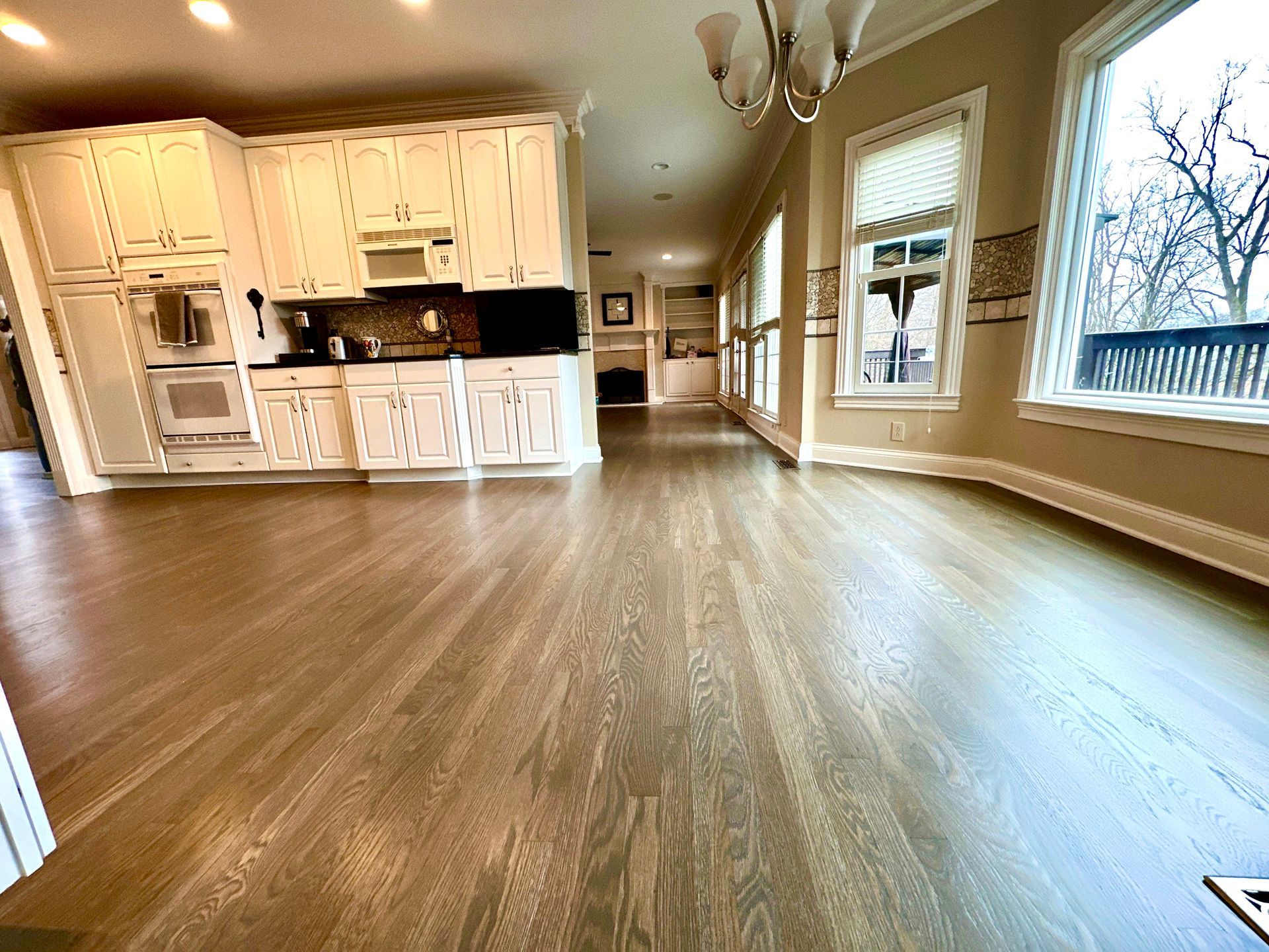 A large empty kitchen with hardwood floors and white cabinets.