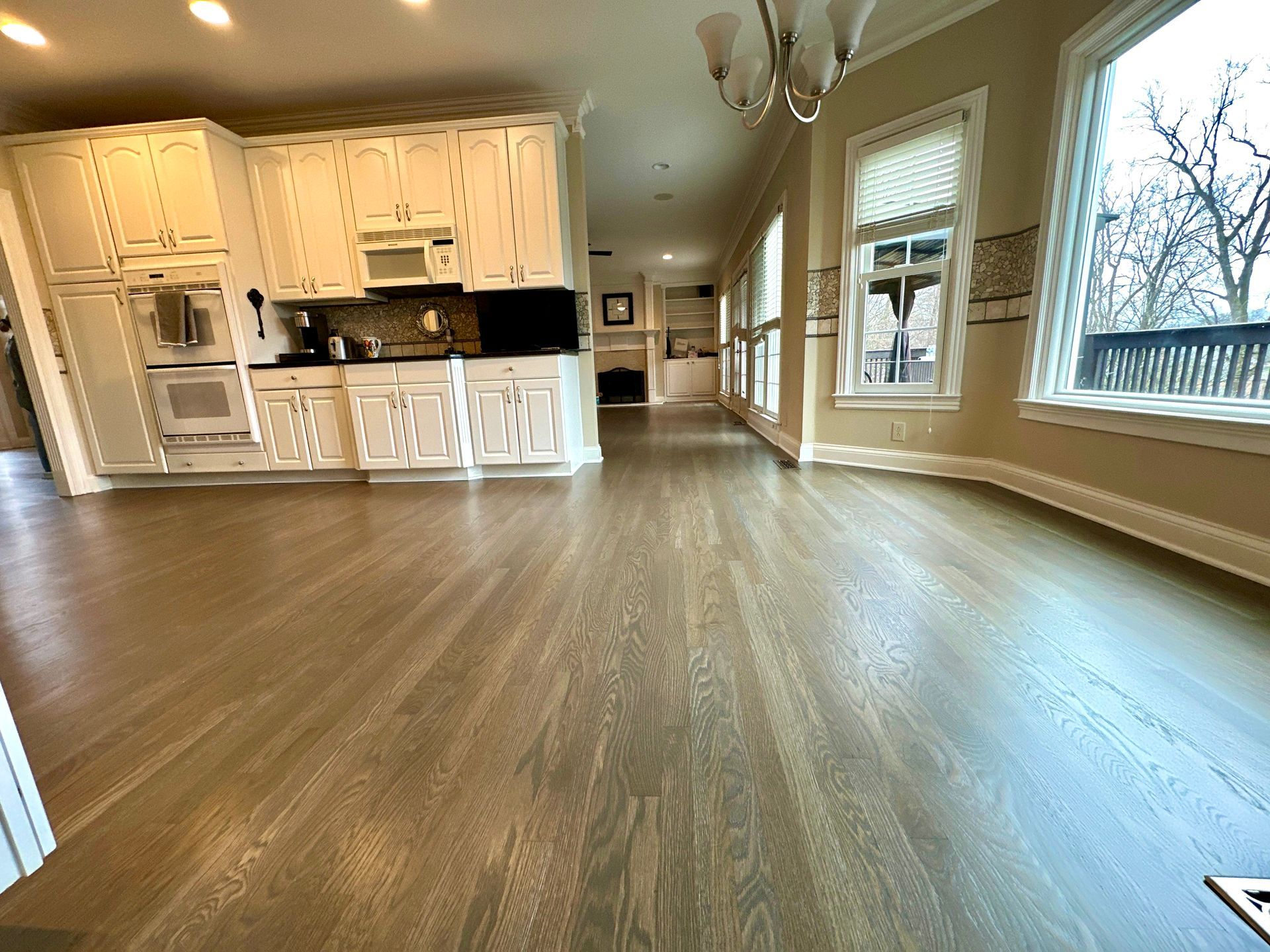 A large empty kitchen with hardwood floors and white cabinets.